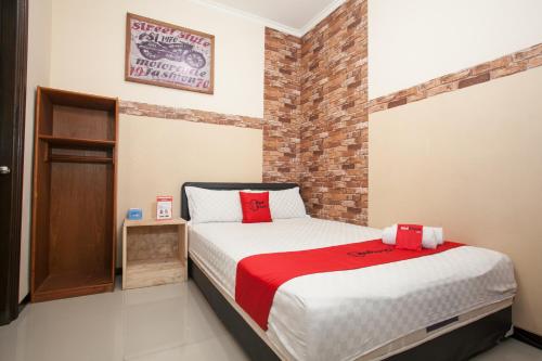 ein Schlafzimmer mit einem Bett und einer Ziegelwand in der Unterkunft RedDoorz At Omah Wetan Sawojajar Malang in Malang