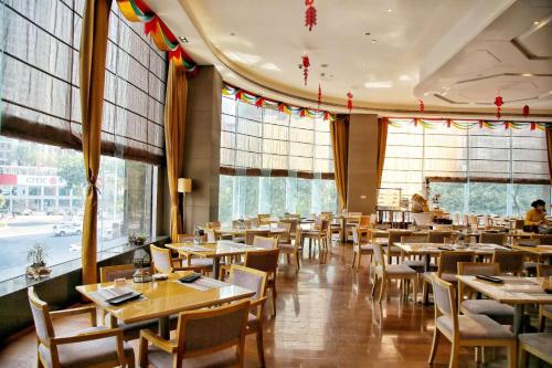 a restaurant with tables and chairs and large windows at Vaperse Hotel Guangzhou Zhujiang New Town - Free Shuttle Bus & Registration Counter During Canton Fair in Guangzhou