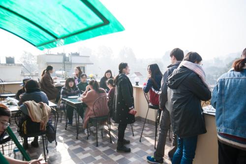 een groep mensen die aan een tafel op een patio zitten bij Be Here Now in Kathmandu