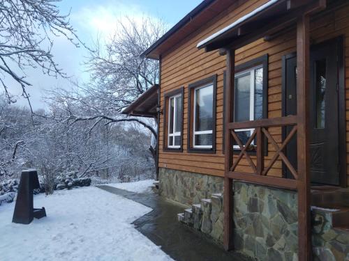 a log cabin with snow on the ground at Country House Kosiv in Kosiv
