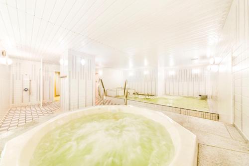 a bathroom with a large tub with green water at Hotel Hanshin Osaka in Osaka