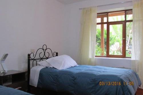 a bedroom with a bed with a blue blanket and a window at Casona Mollepata in Mollepata