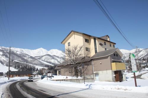 a building on the side of a road in the snow at Hakuba Panorama Hotel in Hakuba