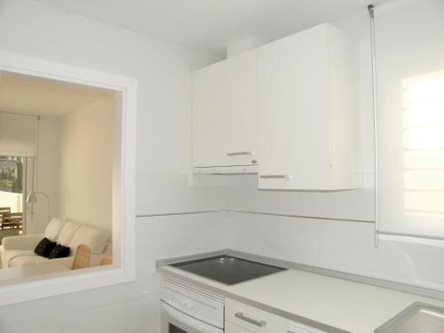 une cuisine blanche avec des armoires blanches et une fenêtre dans l'établissement Apartamentos Doña Carmen, à Malaga