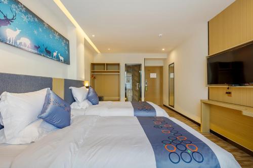 a bedroom with a large white bed with a flat screen tv at Yimi Inn Changdi Damalu Branch in Guangzhou