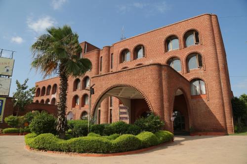 a brick building with a palm tree in front of it at Magsons Resorts in Vrindāvan