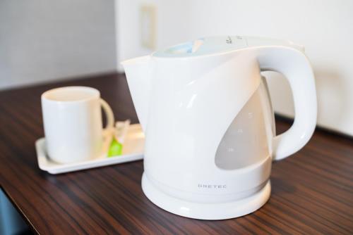 a white coffee maker sitting on a wooden table at Super Hotel Okinawa Nago in Nago