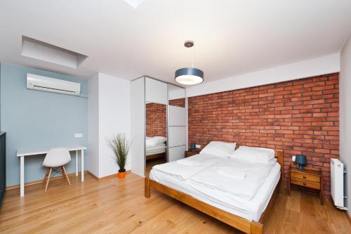 a bedroom with a brick wall and a bed at Apartamenty Sun & Snow Olimp Apartments in Krakow