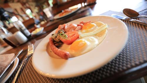 a plate of food with eggs and tomatoes on a table at Shayamoya Tiger Fishing and Game Lodge in Pongola Game Reserve