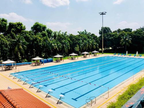 a large swimming pool with tables and umbrellas at Orchid Country Club in Singapore