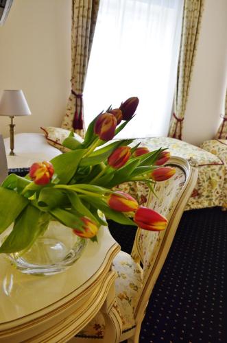 a vase of flowers on a table next to a bed at Pałac Zegrzyński in Zegrze