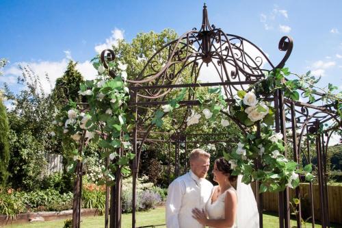 a bride and groom standing under an arch with flowers at The Old Barn Inn in Newport