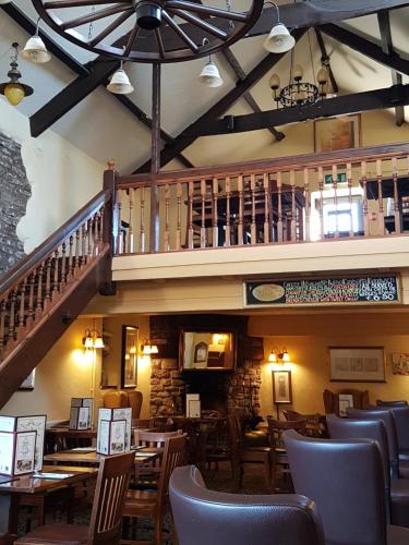 a restaurant with wooden tables and chairs and a staircase at The Old Barn Inn in Newport