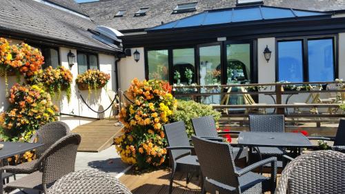 a patio with chairs and tables and flowers at The Old Barn Inn in Newport