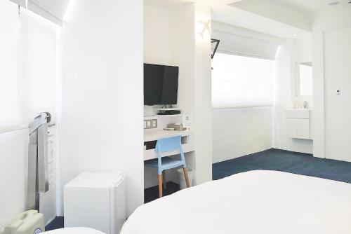 a white bedroom with a bed and a desk at Time Flyer Hotel in Taichung