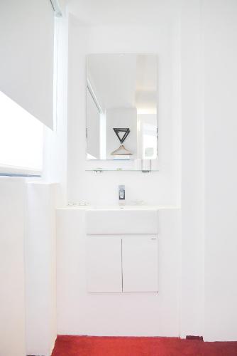 a white kitchen with a sink and a mirror at Time Flyer Hotel in Taichung