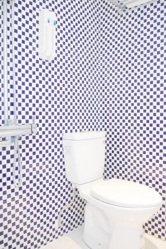 a white toilet in a bathroom with a checkered wall at Time Flyer Hotel in Taichung