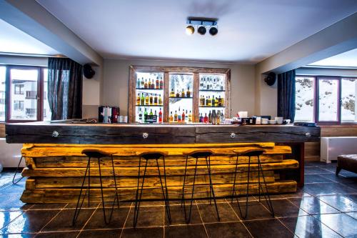 a large wooden bar with stools in a room at Sunny Hills Ski&Wellness in Pamporovo
