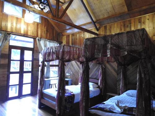 a bedroom with two beds in a room with wooden walls at Borneo Natural Sukau Bilit Resort in Bilit