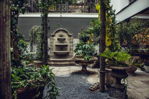 a garden with plants and a statue in the middle at Grand Ferdinand Vienna – Your Hotel In The City Center in Vienna
