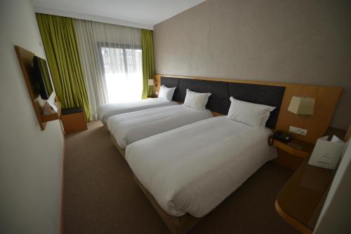 a hotel room with two beds and a window at Annakhil Hotel in Rabat