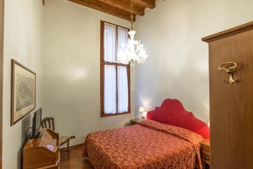 um quarto com uma cama vermelha e uma janela em Hotel Piccola Fenice em Veneza