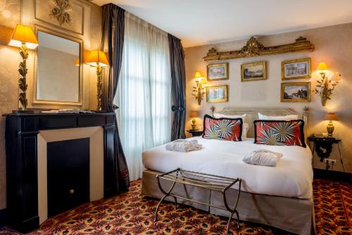 a bedroom with a large white bed and a mirror at H&ocirc;tel Chateaubriand in Paris
