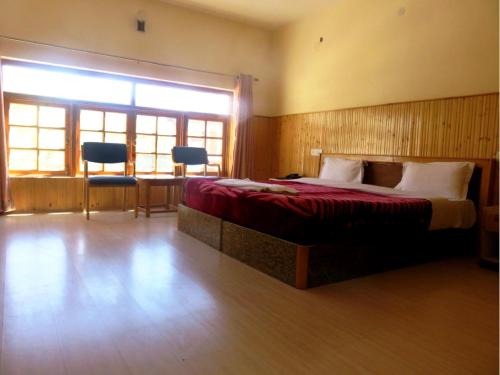 a bedroom with a bed and a table and chairs at Hotel Abu Palace in Leh