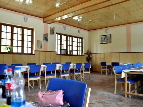 a room with blue chairs and tables and windows at Hotel Abu Palace in Leh