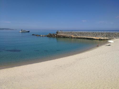 a beach with an umbrella and a boat in the water at Villino Erminia - Seaside Art b&b in Pizzo