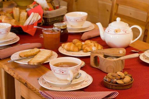 a table with cups and plates of food and pastries at Le Chalet d'en Hô in Névache