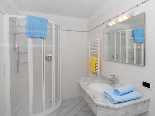 La salle de bains est pourvue d'une douche et d'un lavabo avec des serviettes bleues. dans l'établissement Urthalerhof, à Castelrotto