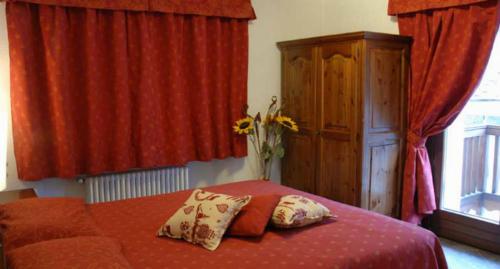 a bedroom with a bed with red sheets and red curtains at Residence Au Vieux Grenier in Cogne