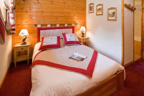 a bedroom with a bed with red and white sheets at Le Chalet d'en Hô in Névache