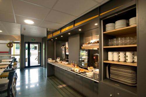 a restaurant with a counter with plates and dishes at B&B HOTEL Moulins in Toulon-sur-Allier