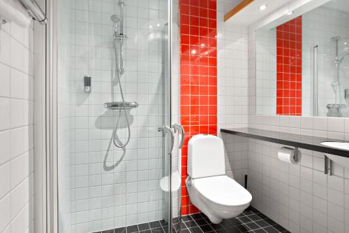 a white toilet sitting next to a shower in a bathroom at Connect Hotel Stockholm in Stockholm