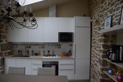 a kitchen with white cabinets and a brick wall at Le Berceul in La Richardais