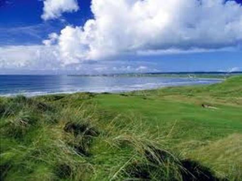 a field of grass with the ocean in the background at Lehinch Lodge in Lahinch