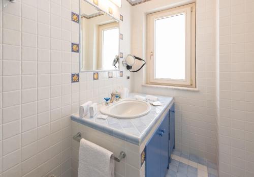 a white bathroom with a sink and a mirror at Villa Le Terrazze Charming Rooms in Taormina