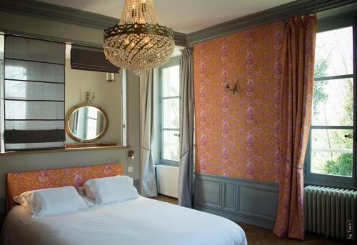 a bedroom with a bed and a chandelier and windows at Chambres d'hôtes de Parseval in Senlis