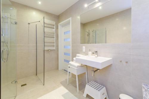 biała łazienka z umywalką i prysznicem w obiekcie Equilibrium Apartments w mieście Ustronie Morskie