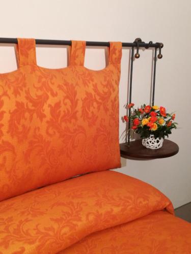 a bed with an orange pillow and a vase of flowers at Dimora Pieri in Florence
