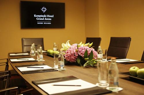 a conference room with a long wooden table with flowers at Kempinski Hotel Grand Arena Bansko in Bansko
