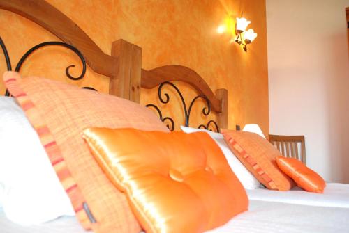 a bed with orange pillows and a wooden headboard at Posada La Fabula in Santillana del Mar