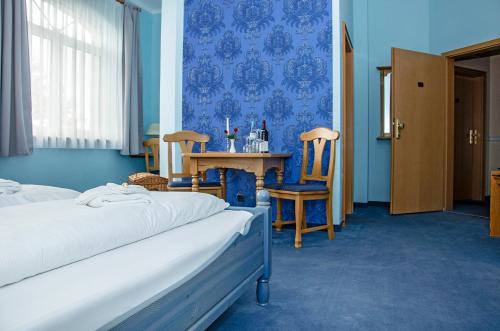 a bedroom with two beds and a table and chairs at Hotel & Restaurant Haus am See in Löcknitz
