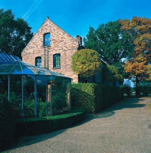 a brick house with a greenhouse in front of it at Orshof in Oudsbergen 