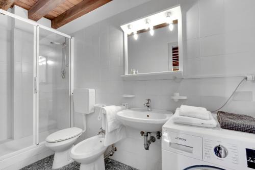 a white bathroom with a toilet and a sink at Peggy Guggenheim Venice Apartment in Venice