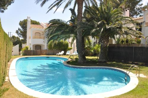 a swimming pool in front of a house with palm trees at Casa Miami Playa in Miami Platja