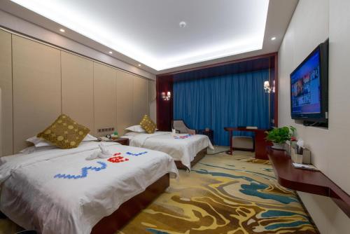 a hotel room with two beds and a flat screen tv at Dunhuang Hotel in Dunhuang