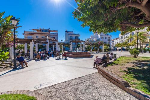 a group of people sitting on benches in a park at Marimel Nerja Alojamientos in Nerja